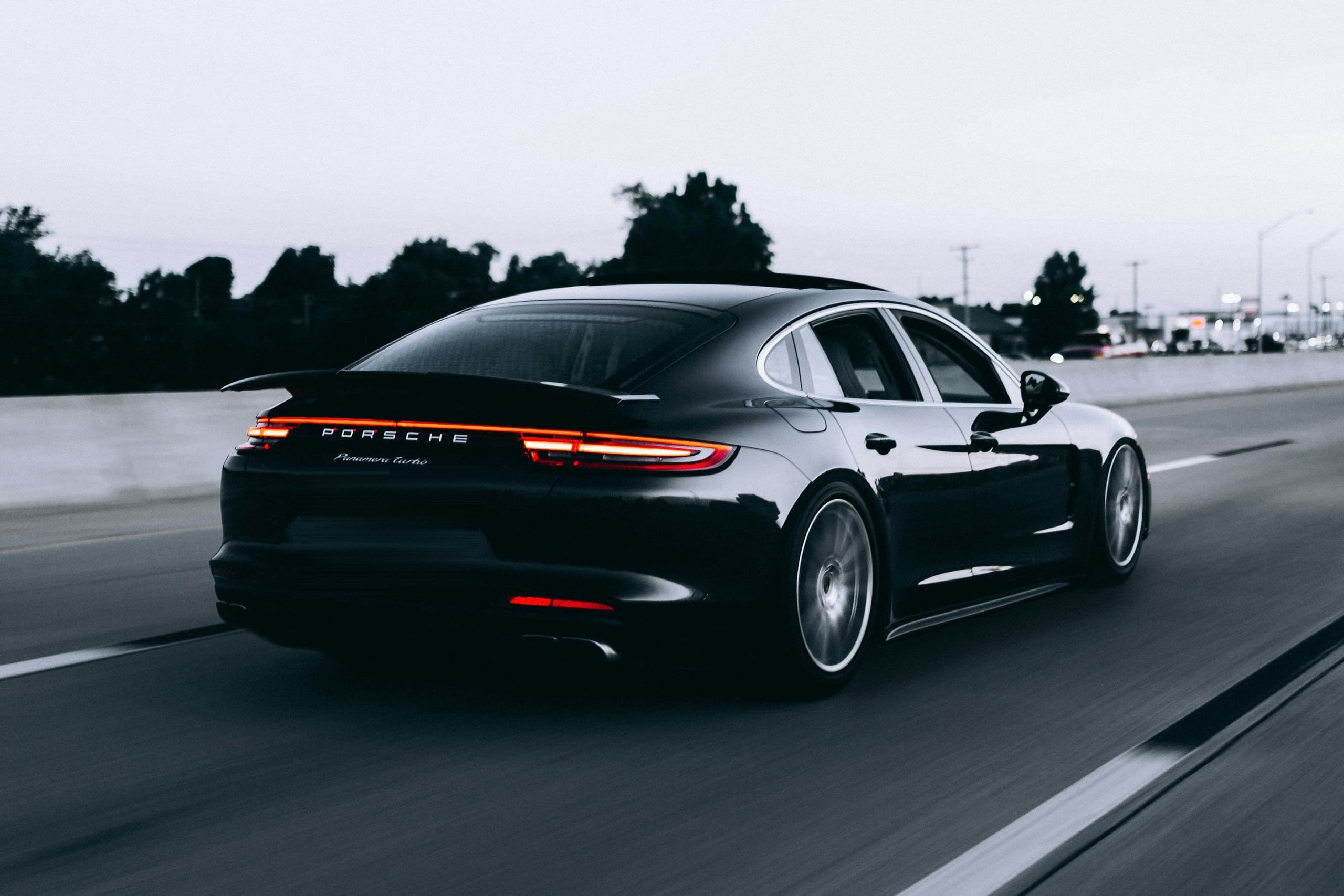 Fotografia de estúdio em tons escuros de um automóvel premium com pintura espelhada e reflexos suaves de iluminação, usada como fundo visual do cabeçalho da página inicial.